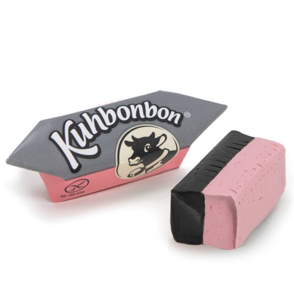 Two pieces of two-layered soft strawberry licorice caramels from the German candy brand Kuhbonbon, one individually wrapped